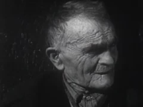 Close-up of an elderly man with weathered face looking toward the camera.