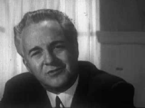 Middle-aged woman speaking, followed by a middle-aged man smiling indoors.