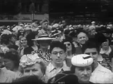 A large crowd of people outdoors, including several individuals wearing hats.