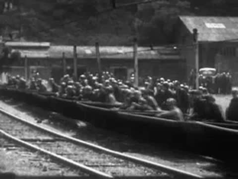 Workers loading materials onto a flatbed railway car at an industrial site