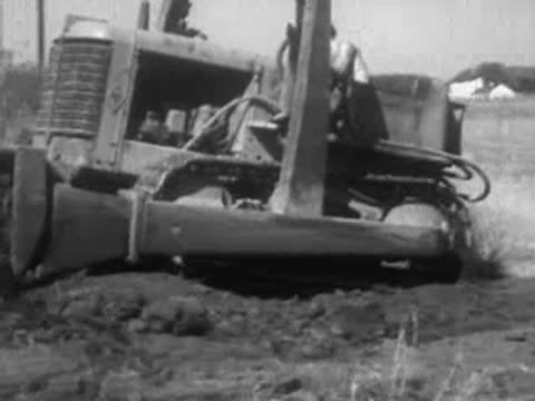 A vintage bulldozer pushing dirt in an open field, agricultural or construction work