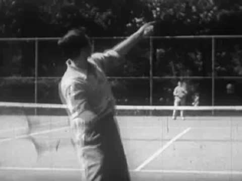 Person practicing tennis strokes on a court with wire fence backdrop