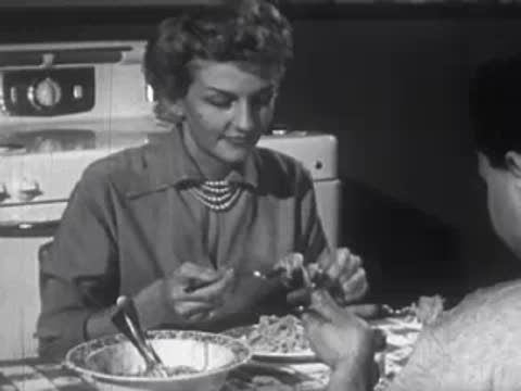 Woman eating a meal at a kitchen table with a stove in the background