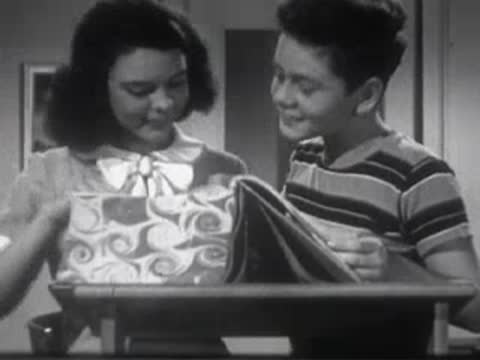 Boy and girl sitting together and looking down at a book on a desk