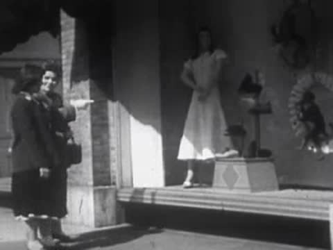 Two women standing outside a storefront window display of mannequins