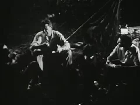 Group of people sitting and talking around a campfire at night