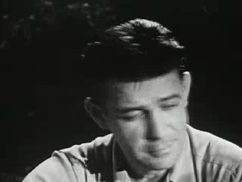 Close-up profile of a man talking near a campfire at night