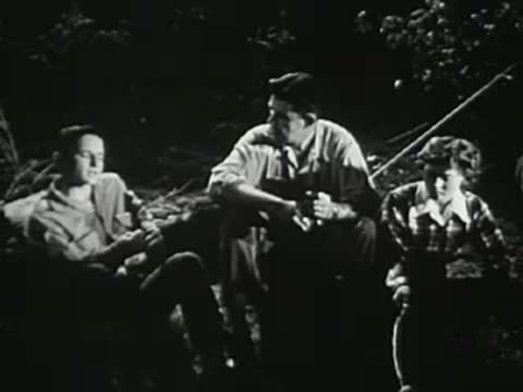 Group of young people sitting and conversing around a campfire