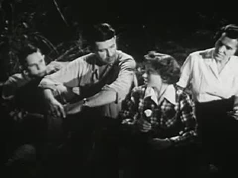 Group of young people sitting closely together around a campfire