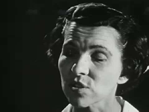 Woman talking outdoors at night, mid-20th-century hairstyle and shirt