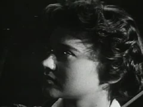Teenage girl looking off-camera, talking, outdoors at night