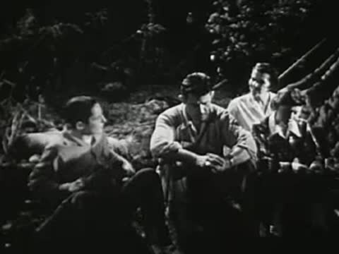Group of people sitting together outdoors at night, listening and talking