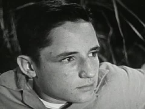 Teenage boy looking thoughtfully outdoors at night, mid-20th-century shirt