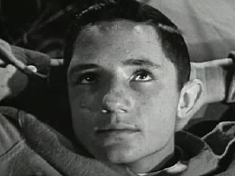Teenage boy lying down outdoors, looking up thoughtfully, hands behind head