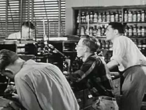 Students working in a science laboratory, vintage glassware and equipment on desks