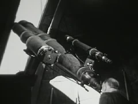 Astronomer looking through a large telescope in an observatory dome