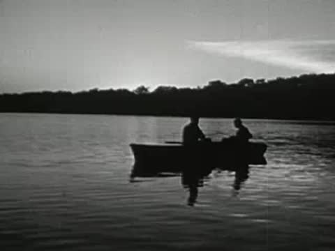 Two people in a small boat on a lake at sunrise