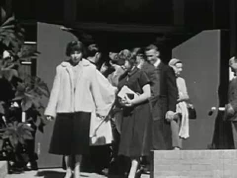 People walking through a doorway, guests arriving at an event or venue, vintage attire