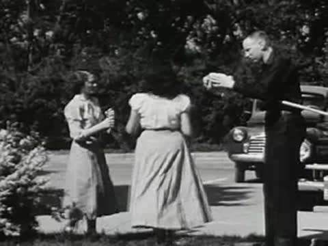 People standing outdoors near cars, vintage clothing, sunny day setting