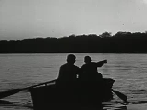 Two people in a rowboat on a lake at sunrise