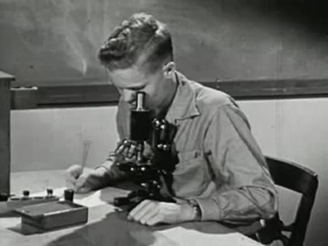 Student looking through a microscope in a classroom setting, school laboratory equipment
