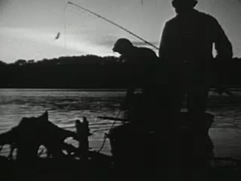People fishing and handling equipment near a lake at sunrise