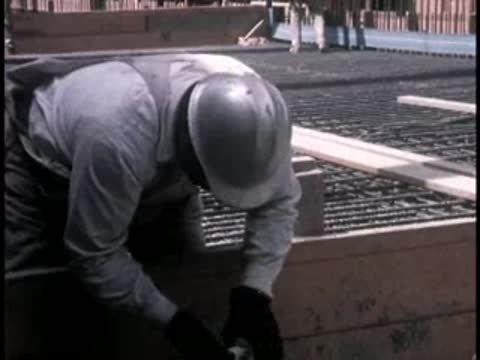 A construction worker in a hard hat inspecting metal rebar forms.
