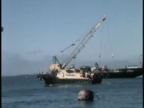 A floating crane on a body of water near a distant shoreline.