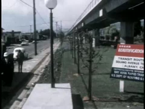 A bus driving past a roadside promotional sign for a beautification project.