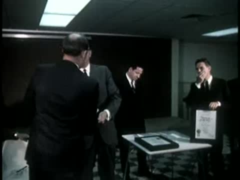 Group of men shaking hands and holding certificates indoors