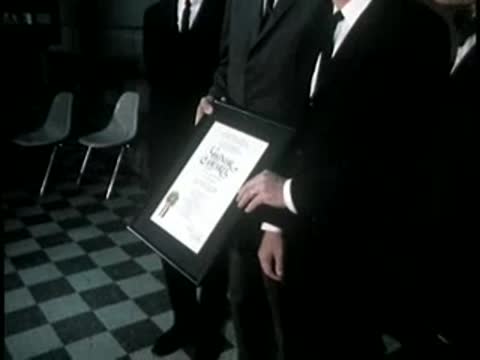 Men in dark suits standing and holding certificates