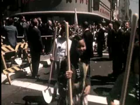 Crowd of people holding ceremonial shovels on a city street