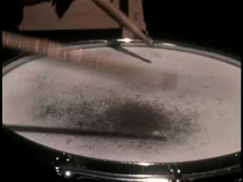 Close-up of drumsticks hitting a snare drum