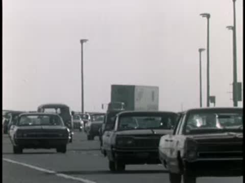 Heavy traffic on a multi-lane highway with vintage cars.