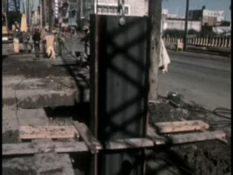 Vertical steel I-beam pillar installed in urban construction setting.
