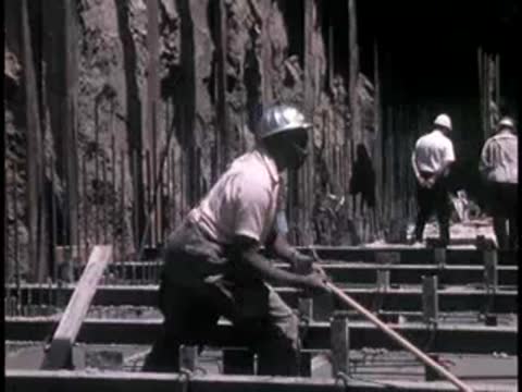 Construction workers pouring concrete and handling equipment on site.