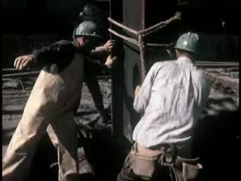 Construction workers positioning and securing a large steel column.
