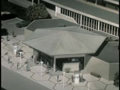 Modern single-story commercial building exterior with plaza and light posts.