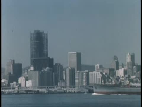 City skyline view across a waterfront with a large ship.