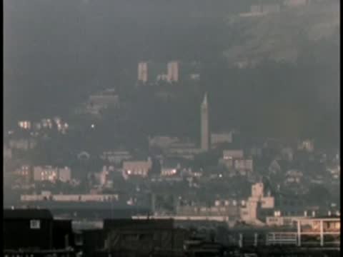 Cityscape view from a distance with buildings and lights under a hazy sky.