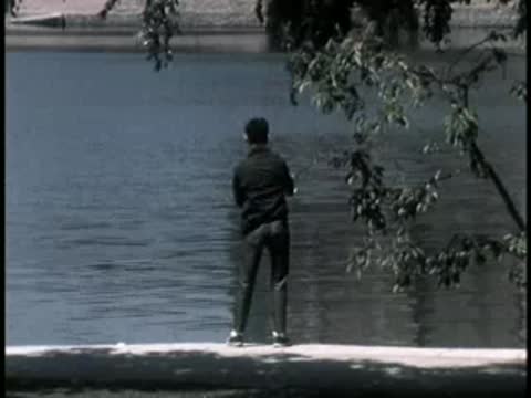 Person fishing with a rod near the edge of a body of water.