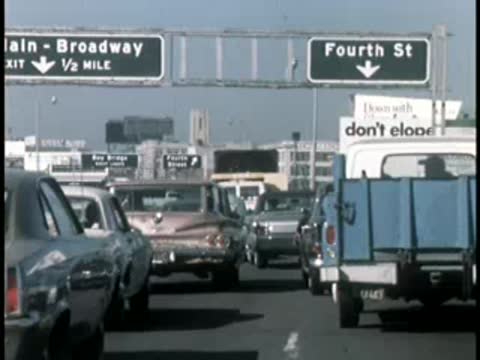 Cars driving on highway with overhead street name signs.