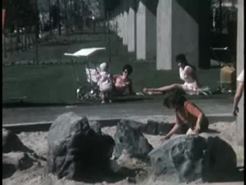 Children playing in a sandbox area with concrete structures nearby.