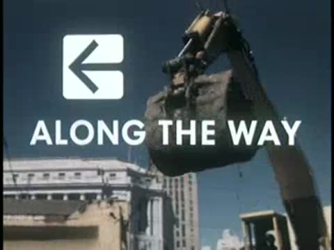 Excavator loading dirt against urban background