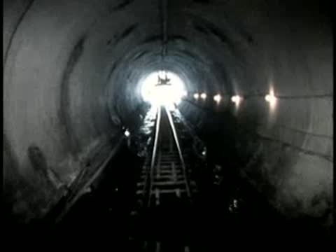 View moving through a brightly lit railway tunnel toward the exit.
