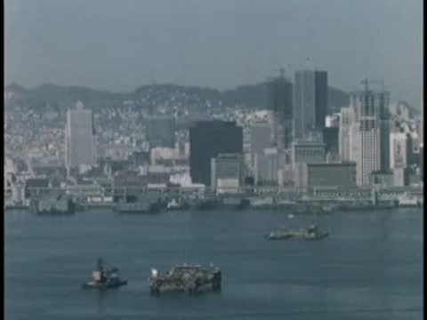 Waterfront view of a city skyline with buildings and boats.