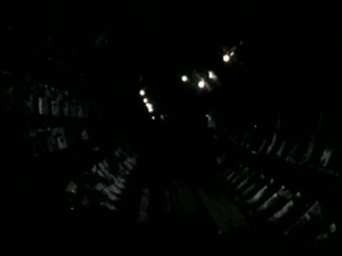 Dark interior view with bright overhead tunnel lights.