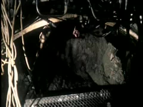 A large pile of excavated earth and rock inside a dark underground area.