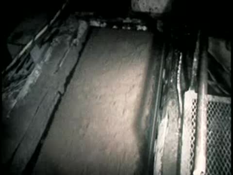 A conveyor belt moves dirt and excavated material through a narrow underground space.