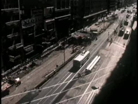 An elevated high-angle view shows traffic flowing along a bustling city street.